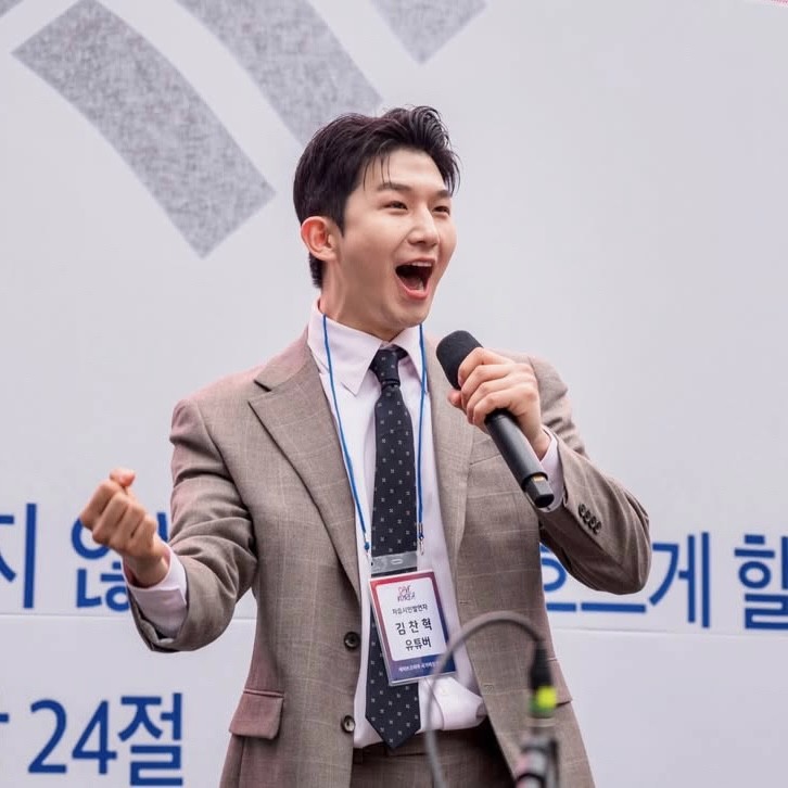 집회 무대에서 마이크를 들고 연설하는 모습